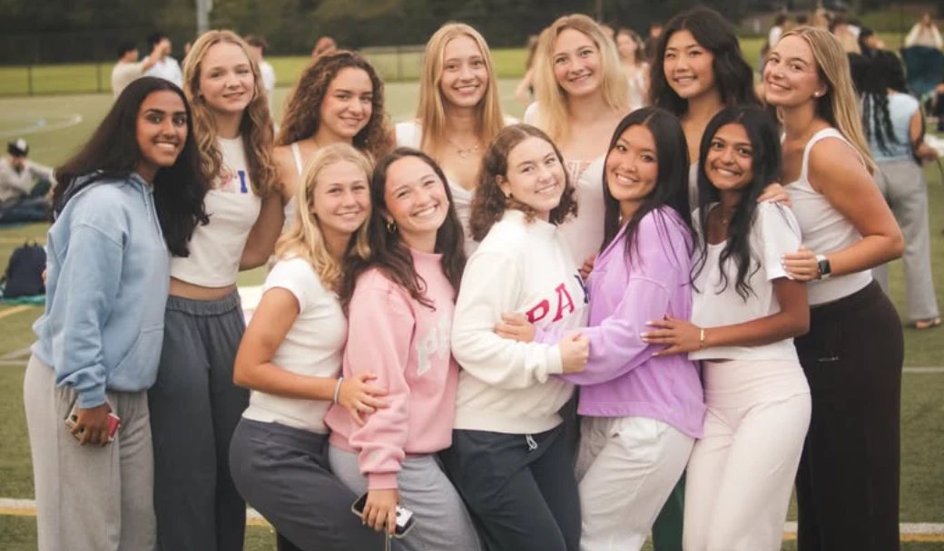 A group of seniors with their arms around each other on the turf field at senior sunrise