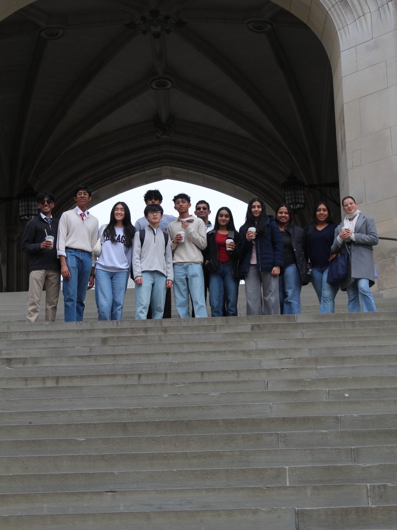 The Model UN team at the top of a wide stone staircase under a Gothic arch
