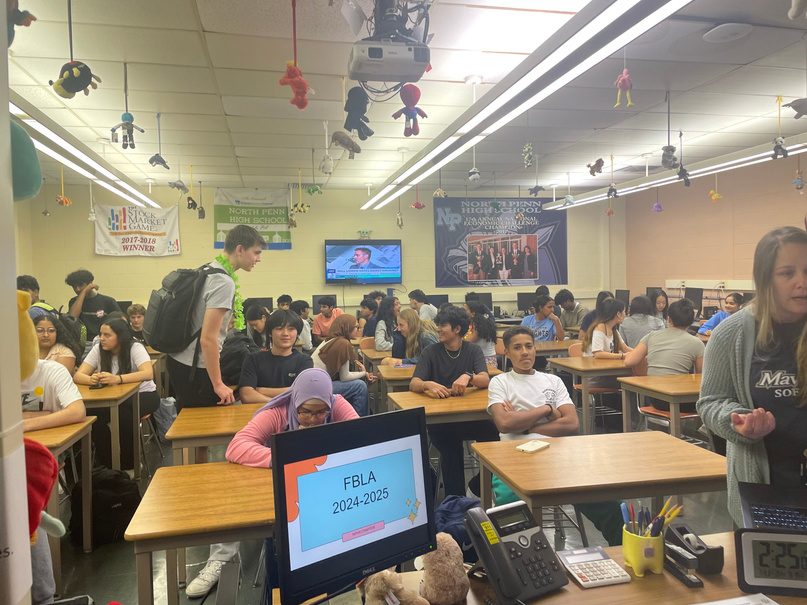 A chapter meeting in a school classroom: members at the tables, an FBLA 2024-2025 slide on the screen